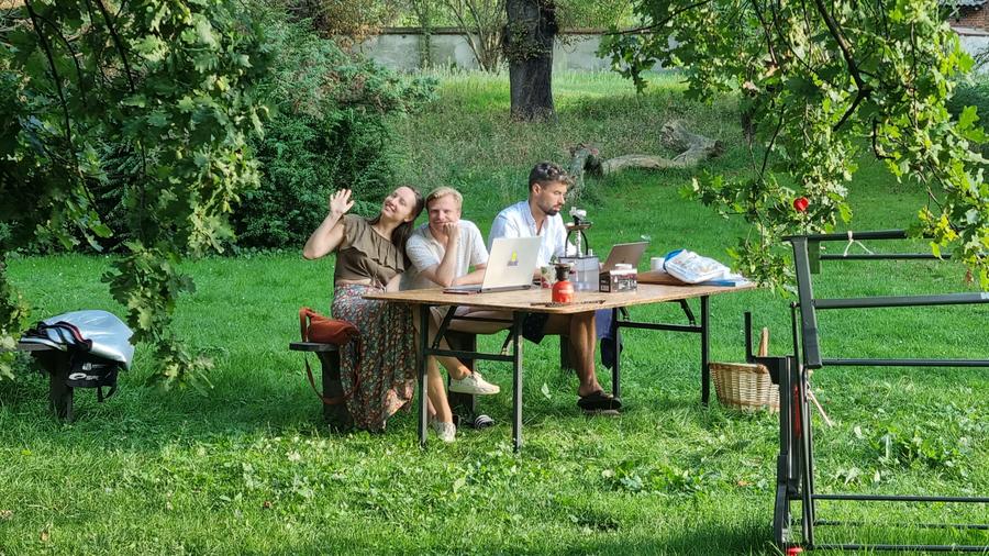 Communal dinner at a long table under the trees in the palace park