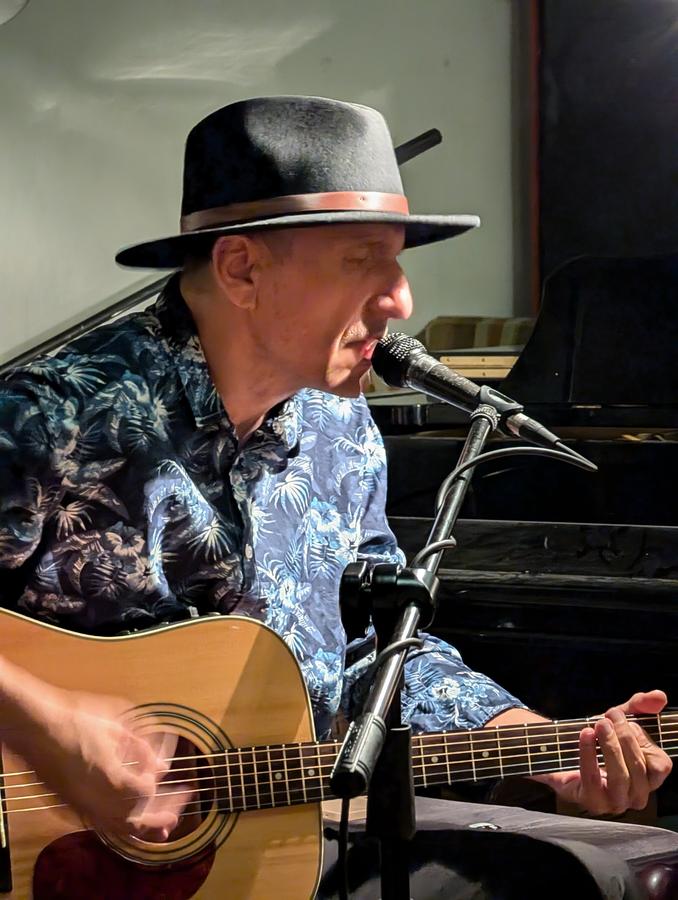 Musician playing guitar and singing at Open Blues